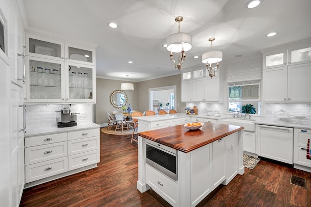 kitchen featuring dishwasher, a peninsula, butcher block counters, stainless steel microwave, and ornamental molding
