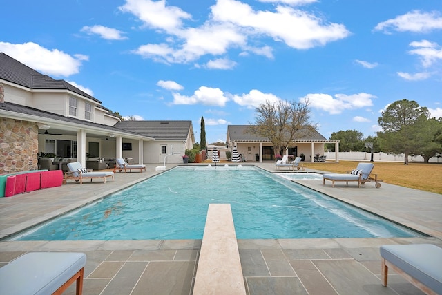 view of pool with a fenced in pool, a diving board, a ceiling fan, and a patio area