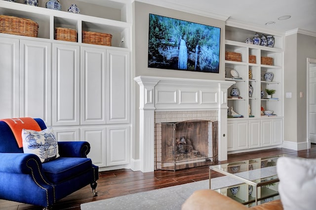living room featuring a fireplace, wood finished floors, built in features, baseboards, and ornamental molding