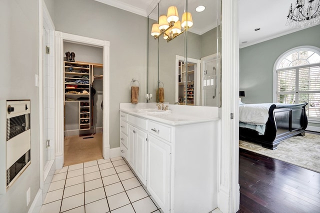 ensuite bathroom featuring a notable chandelier, heating unit, a walk in closet, and crown molding