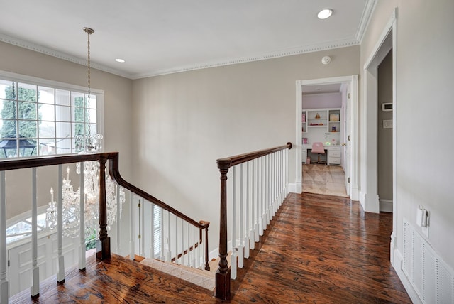 hallway with an upstairs landing, visible vents, and wood finished floors