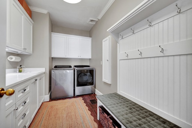 washroom with crown molding, a sink, cabinet space, washing machine and dryer, and wood finished floors