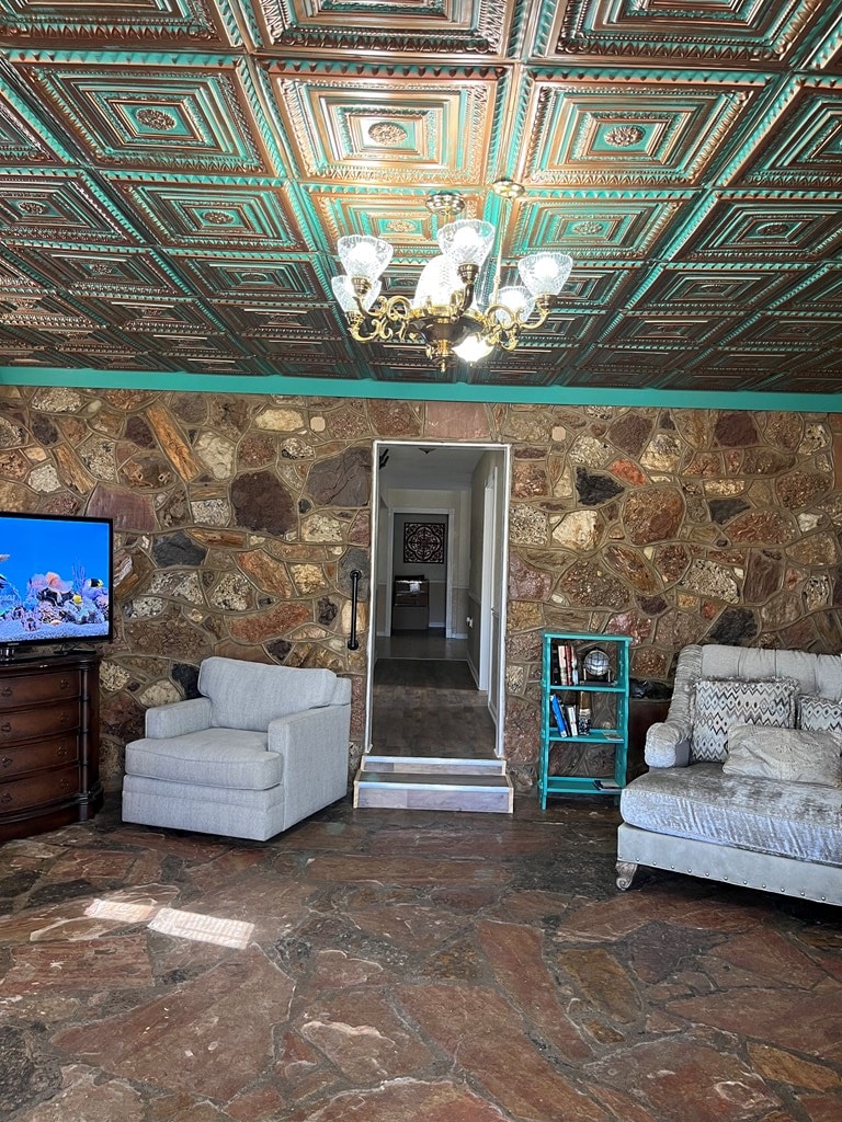 sitting room with a chandelier and stone finish flooring