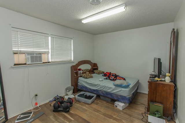 bedroom with hardwood / wood-style floors, cooling unit, and a textured ceiling