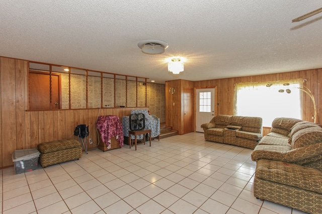 living room with light tile patterned flooring, a textured ceiling, and wooden walls