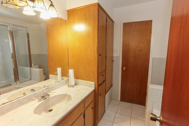 bathroom with tile patterned floors, vanity, a chandelier, and tile walls