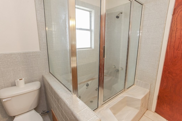 bathroom with toilet, bath / shower combo with glass door, and tile walls