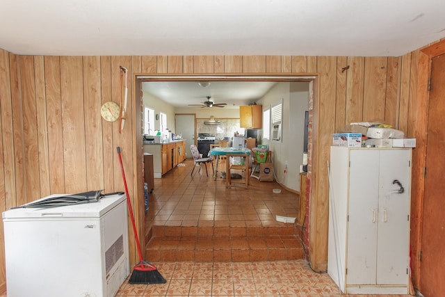 kitchen with ceiling fan, wood walls, and gas range