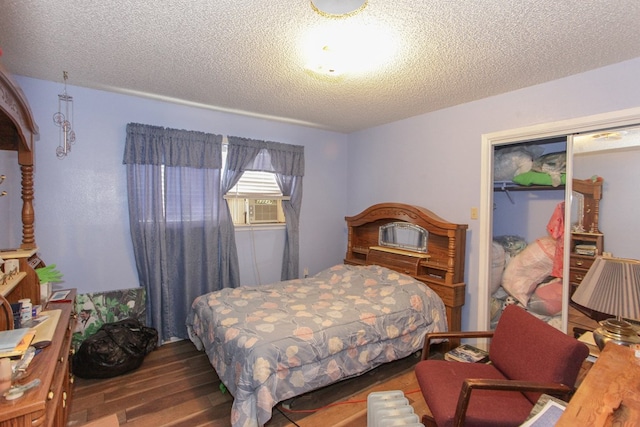 bedroom featuring cooling unit, wood-type flooring, a textured ceiling, and a closet