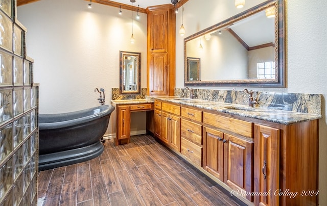 bathroom with hardwood / wood-style flooring, a washtub, crown molding, and vanity