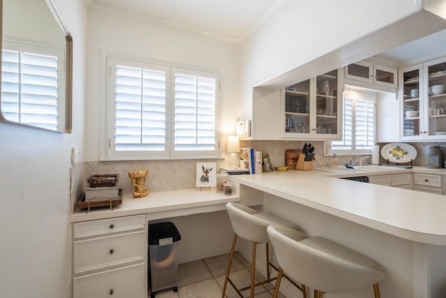 2209 Shell Ave, Midland, TX 79705 - kitchen featuring decorative backsplash, a sink, white cabinetry, a breakfast bar area, and crown molding