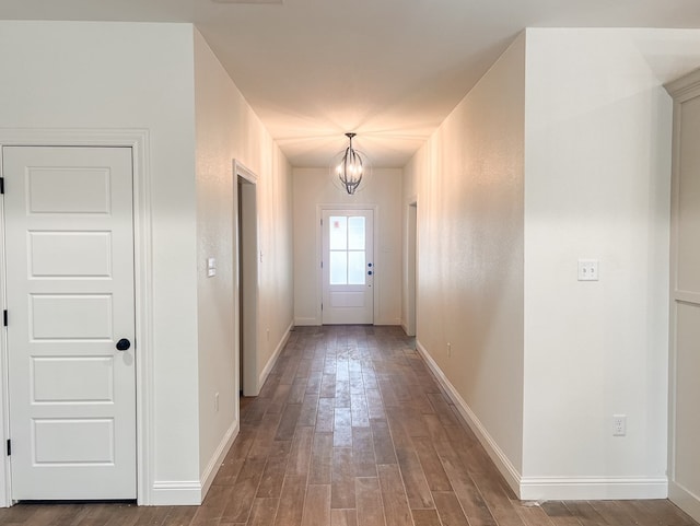 doorway with baseboards, a chandelier, and wood finished floors