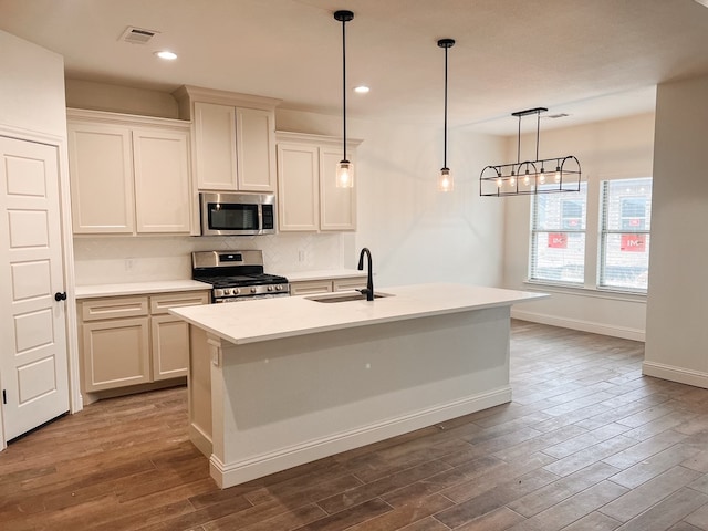 kitchen featuring dark wood-style floors, stainless steel appliances, light countertops, visible vents, and a sink