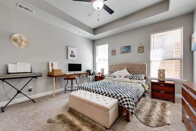 bedroom featuring baseboards, carpet flooring, a tray ceiling, and visible vents