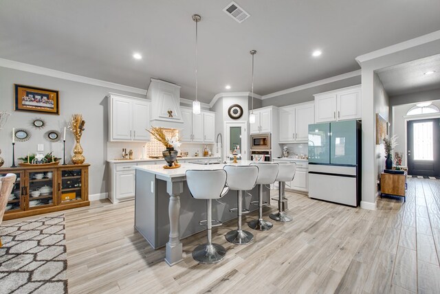 kitchen with light countertops, visible vents, stainless steel microwave, tasteful backsplash, and refrigerator with glass door
