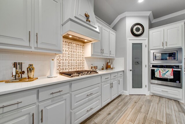 13 La Cresta Ave, Odessa, TX 79765 - kitchen with stainless steel appliances, white cabinets, light countertops, crown molding, and light wood-style floors