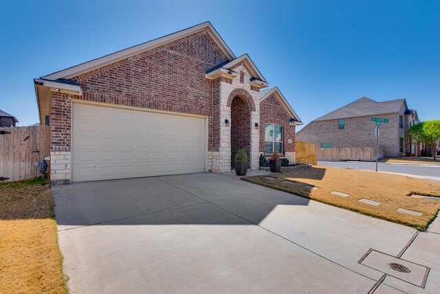 view of front facade featuring concrete driveway, fence, an attached garage, stone siding, and brick siding