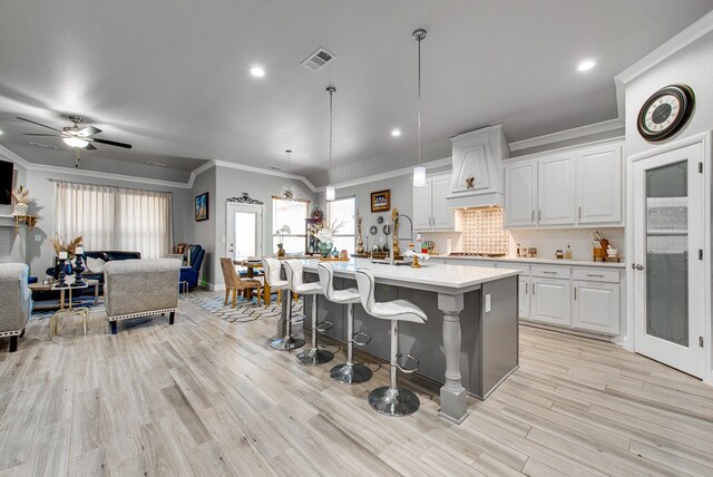 13 La Cresta Ave, Odessa, TX 79765 - kitchen featuring crown molding, open floor plan, premium range hood, light countertops, and light wood-type flooring