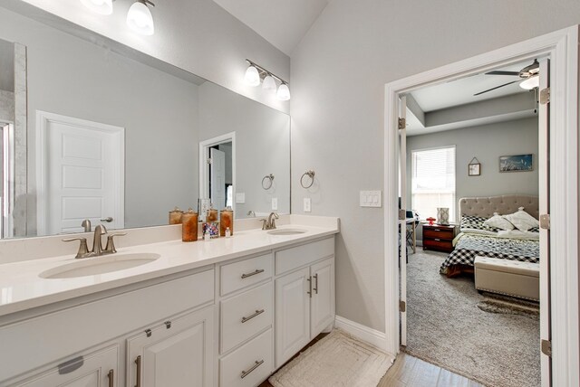 bathroom with ensuite bathroom, double vanity, a sink, and a ceiling fan