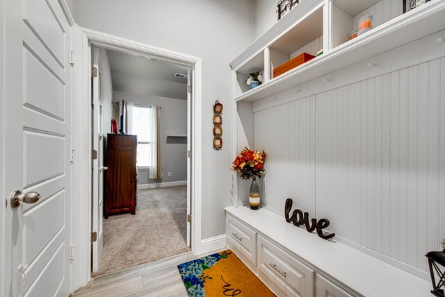 mudroom featuring light colored carpet, baseboards, light wood finished floors, and visible vents