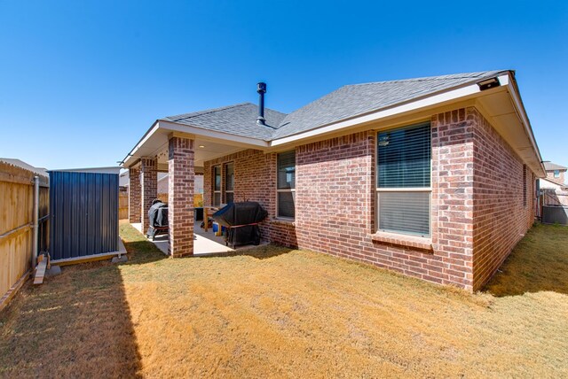 back of house featuring a yard, brick siding, fence, and a patio area