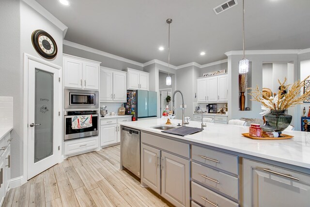 13 La Cresta Ave, Odessa, TX 79765 - kitchen featuring stainless steel appliances, a sink, light countertops, white cabinetry, and crown molding