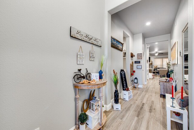 hall featuring light wood-style flooring and baseboards