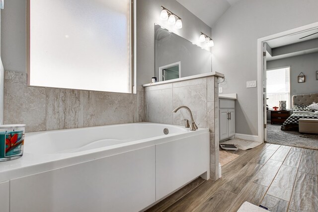 ensuite bathroom featuring vanity, baseboards, ensuite bath, a garden tub, and wood tiled floor