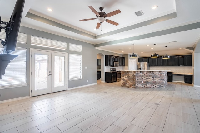 unfurnished living room featuring crown molding, ceiling fan, arched walkways, a raised ceiling, and baseboards