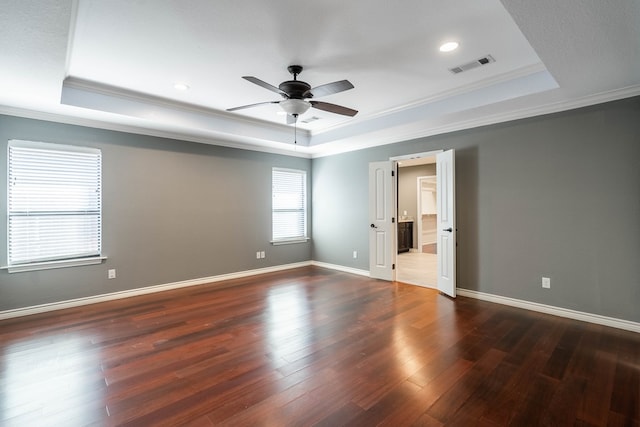 spare room with crown molding, dark hardwood / wood-style floors, ceiling fan, and a raised ceiling