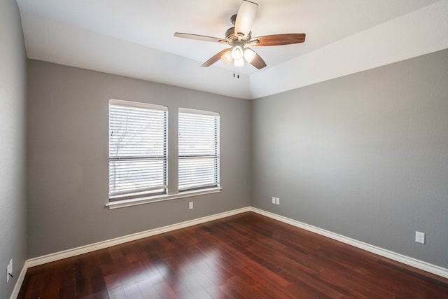 spare room with dark wood-type flooring, ceiling fan, and baseboards
