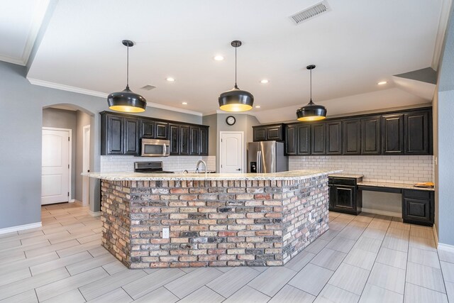 kitchen with hanging light fixtures, an island with sink, appliances with stainless steel finishes, and crown molding