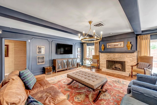 living room with a stone fireplace, an inviting chandelier, and hardwood / wood-style flooring