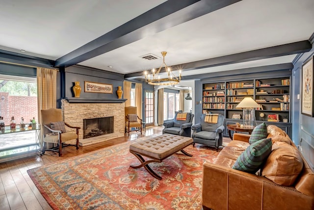 living room with hardwood / wood-style floors, a notable chandelier, beam ceiling, and a fireplace