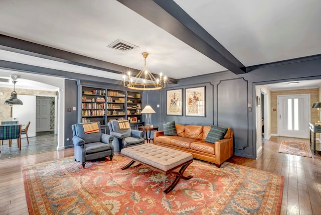 living room with crown molding, built in features, a chandelier, and light wood-type flooring