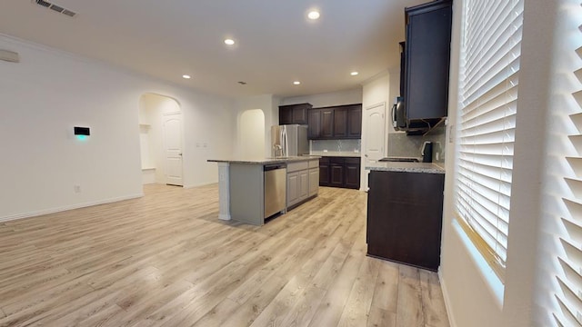 kitchen featuring light hardwood / wood-style flooring, backsplash, stainless steel appliances, a center island, and dark brown cabinetry