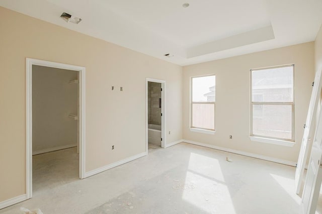 2201 S County Rd 1059, Midland, TX 79706 - unfurnished bedroom featuring a walk in closet, a raised ceiling, baseboards, and connected bathroom
