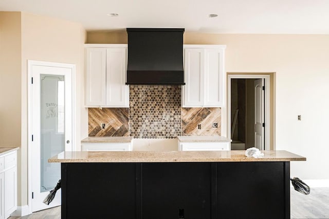 2201 S County Rd 1059, Midland, TX 79706 - kitchen with white cabinetry, light stone counters, premium range hood, and backsplash
