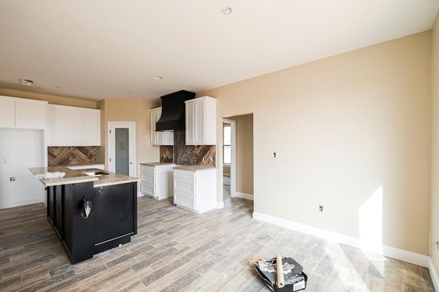 2201 S County Rd 1059, Midland, TX 79706 - kitchen with custom exhaust hood, white cabinets, light wood-style flooring, and backsplash