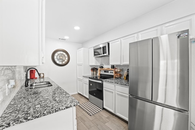 400 Player Ct, Midland, TX 79705 - kitchen with appliances with stainless steel finishes, decorative backsplash, dark stone countertops, white cabinets, and recessed lighting