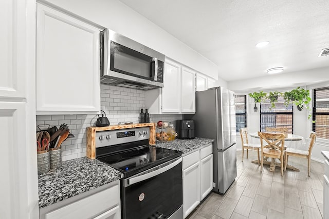 400 Player Ct, Midland, TX 79705 - kitchen featuring appliances with stainless steel finishes, decorative backsplash, dark stone counters, white cabinets, and recessed lighting