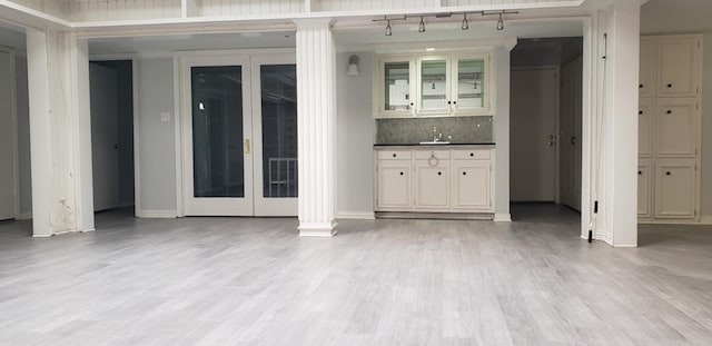 interior space with tasteful backsplash, sink, light hardwood / wood-style floors, and ornate columns