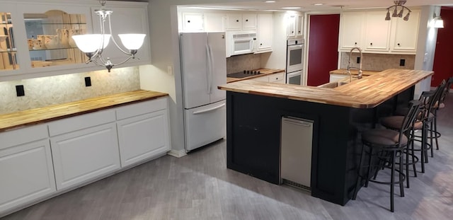 kitchen featuring white cabinetry, white appliances, butcher block counters, and hanging light fixtures