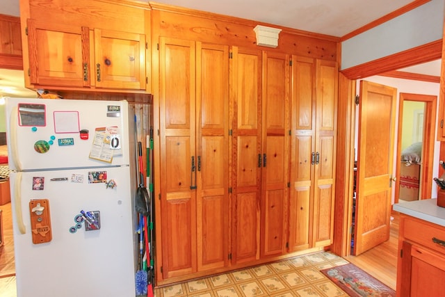 4610 Wasson Rd, Big Spring, TX 79720 - kitchen with freestanding refrigerator, light floors, brown cabinetry, crown molding, and light countertops