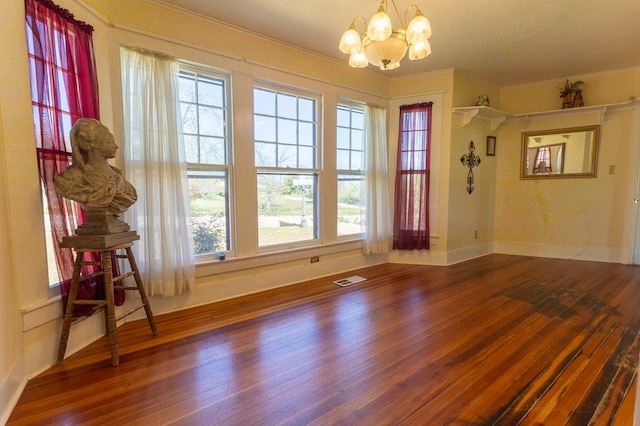 unfurnished dining area featuring crown molding, hardwood / wood-style floors, and a chandelier