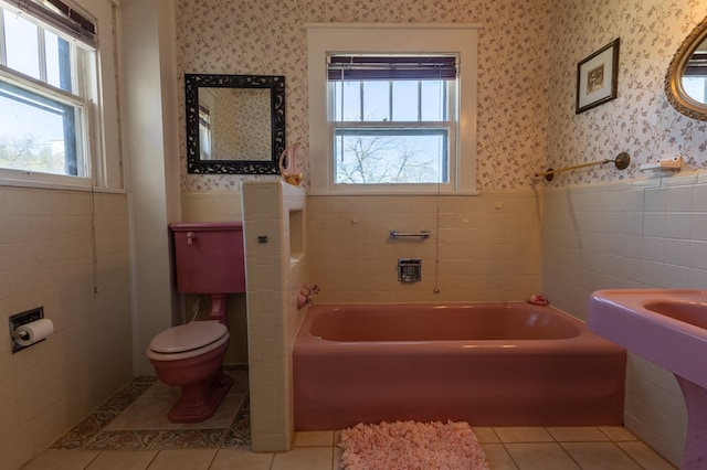 bathroom featuring a tub, tile patterned flooring, tile walls, and toilet