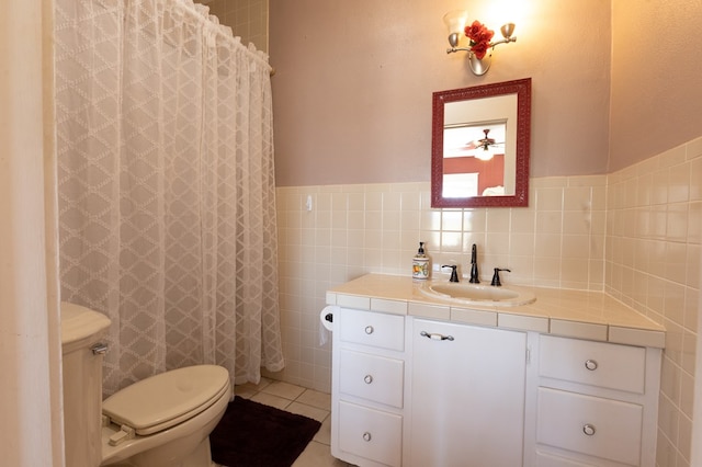 bathroom with toilet, vanity, tile patterned floors, and tile walls