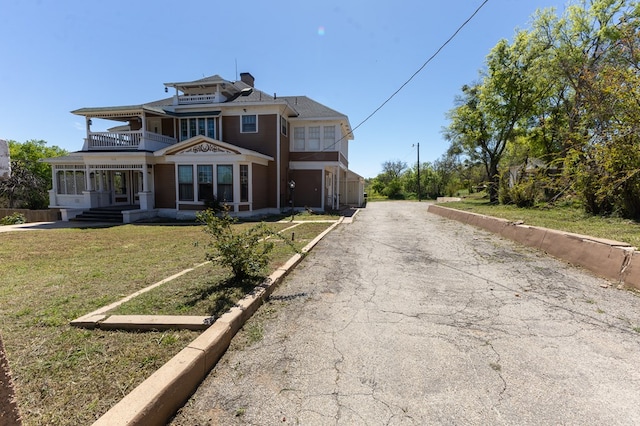 view of front of house featuring a balcony and a front lawn