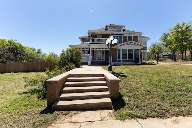 view of front facade featuring a balcony and a front lawn