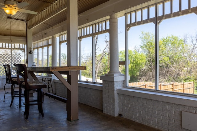 sunroom featuring ceiling fan, ornate columns, and wood ceiling